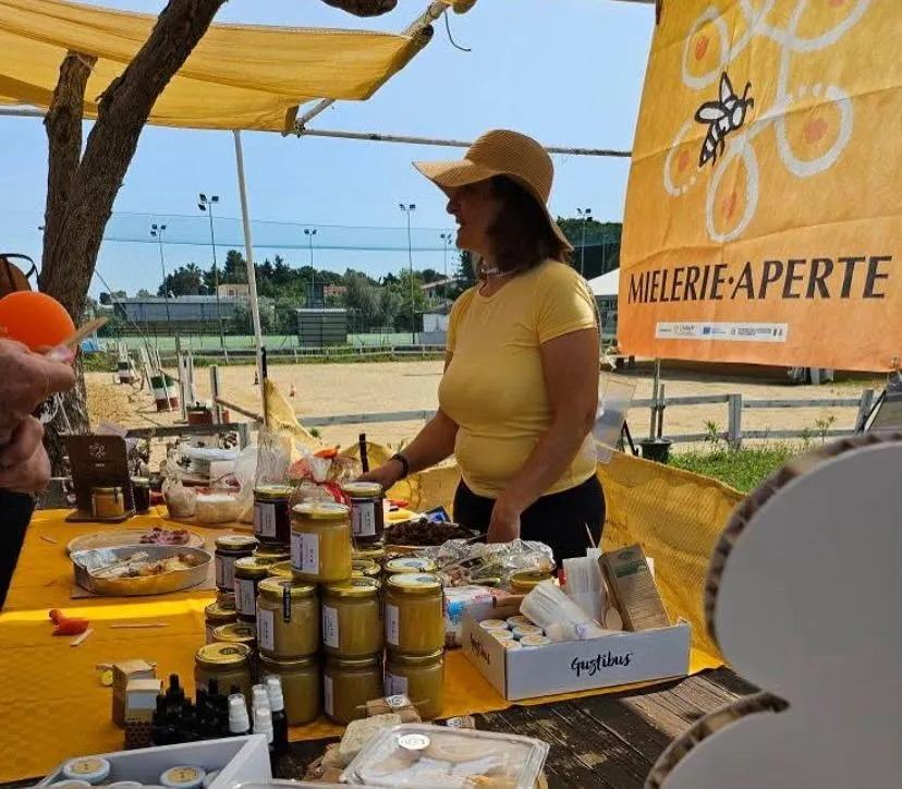 Jars of Agricola Tarantino honey on the tasting stall, with the Mielerie Aperte flag